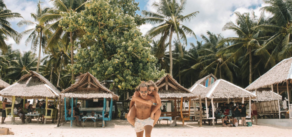 Pareja disfrutando de una playa paradisíaca una vez preparada su mochila para Filipinas